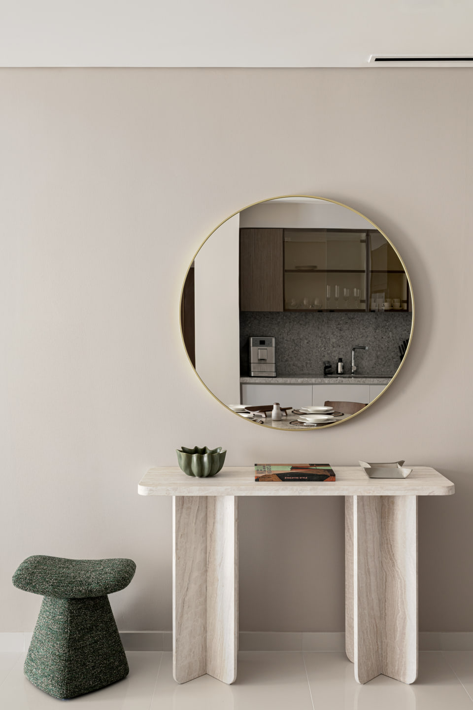 Round mirror above a pale sculptural console