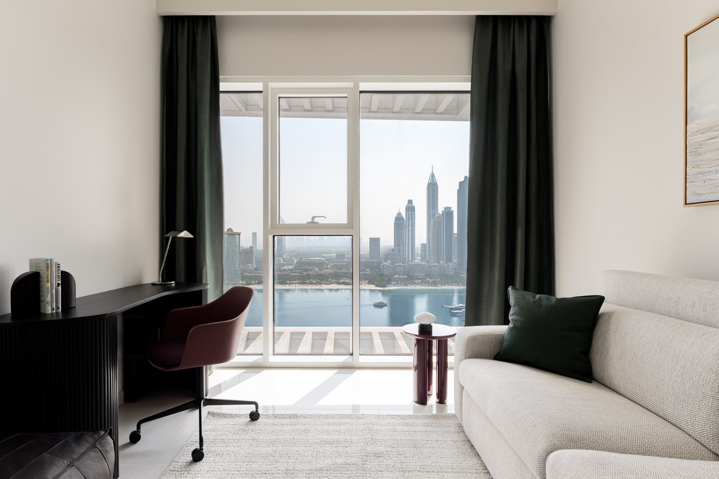 Home office with a curved desk, pale sofa and panoramic Dubai view