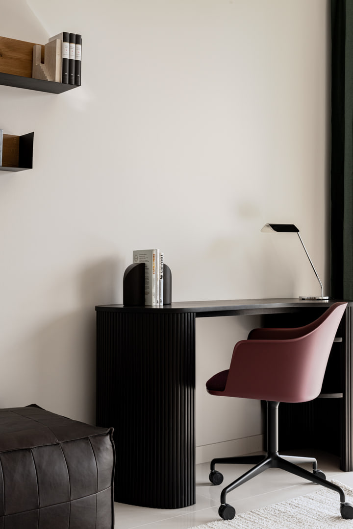 Curved dark timber desk with a burgundy office chair