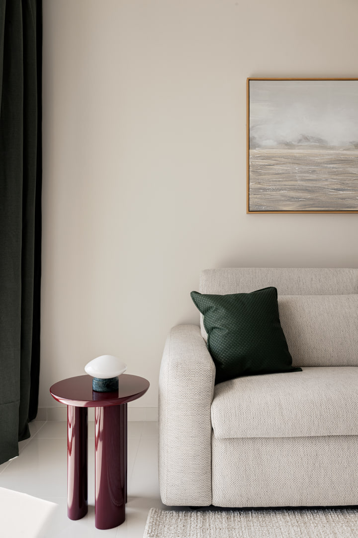 Pale sofa with a green cushion and burgundy side table