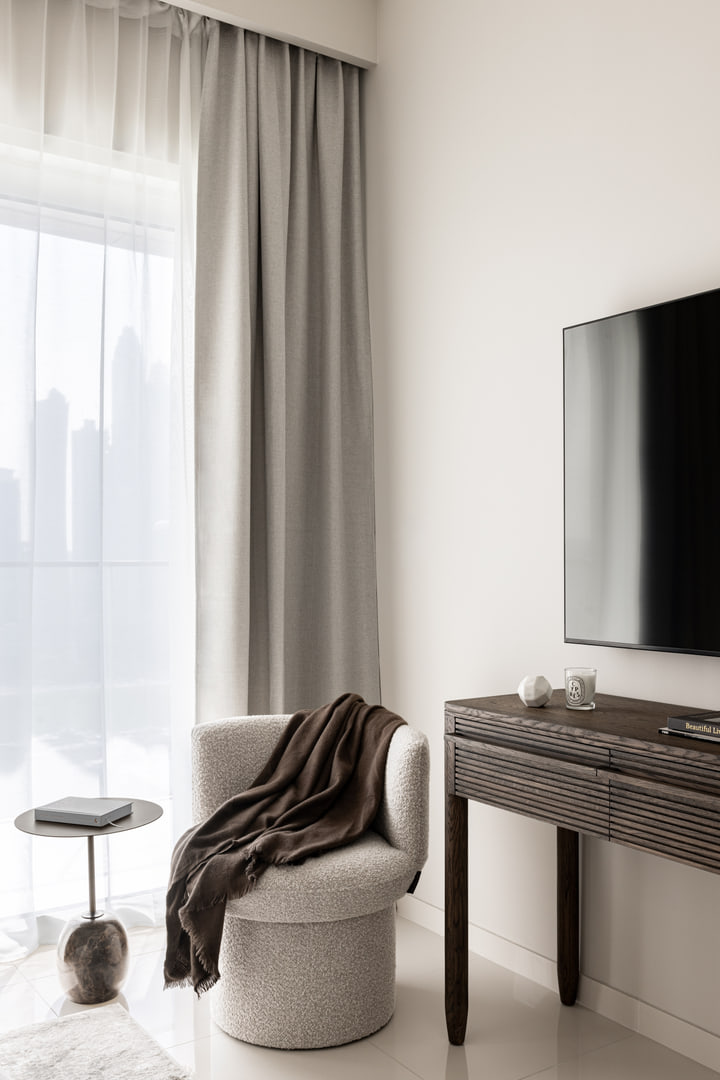 Bedroom television console with a rounded chair beside the window
