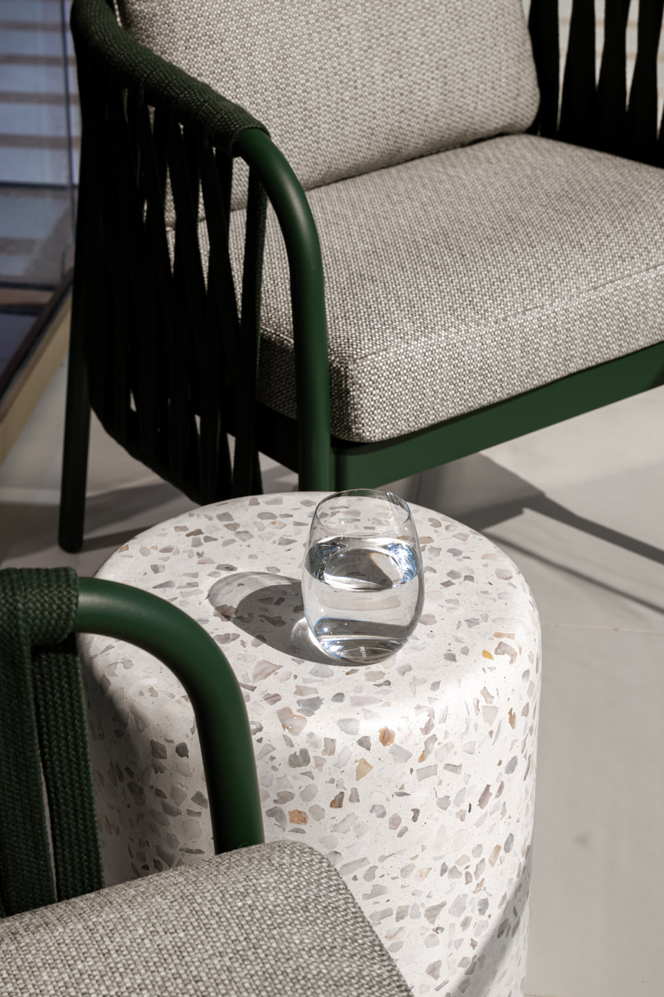 Green balcony chairs around a pale terrazzo side table