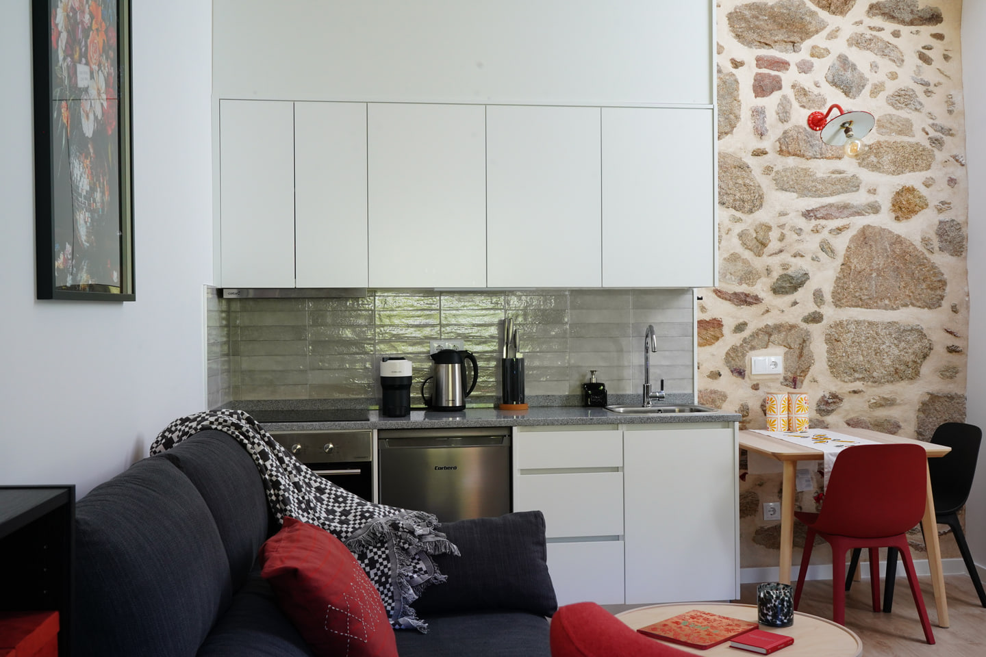 Contemporary white kitchen meeting an original stone wall in the Cerdal house
