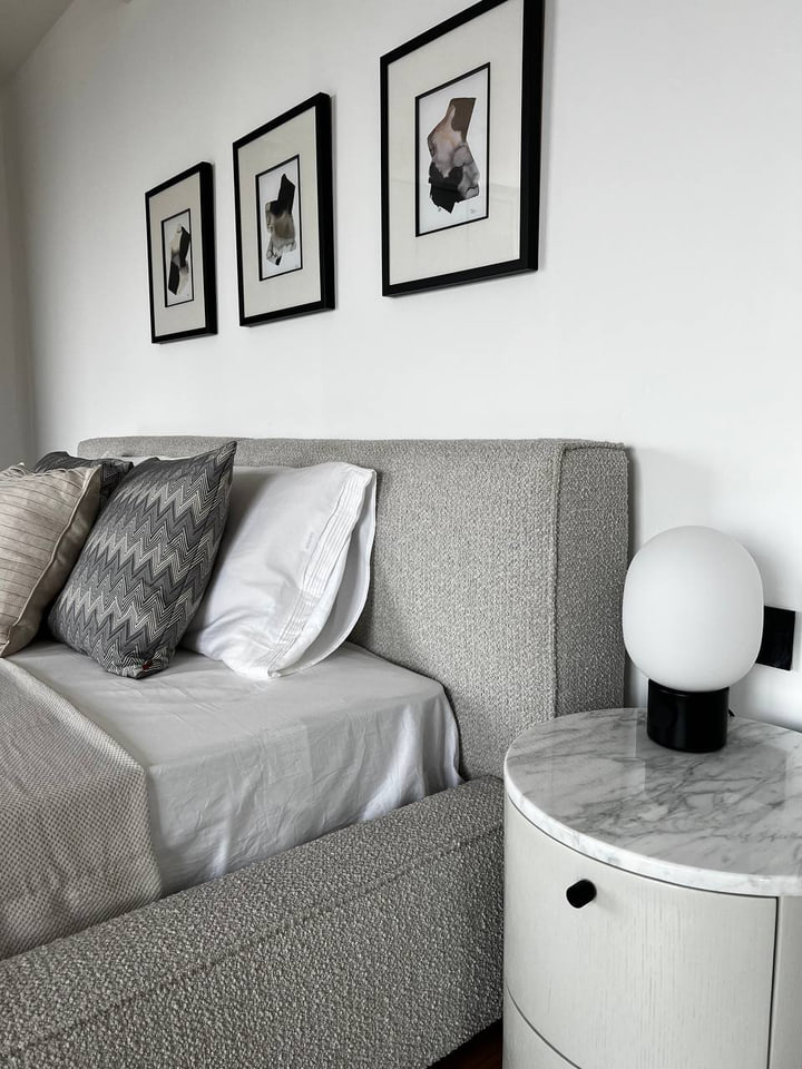 Upholstered bed and rounded stone bedside table with a globe lamp