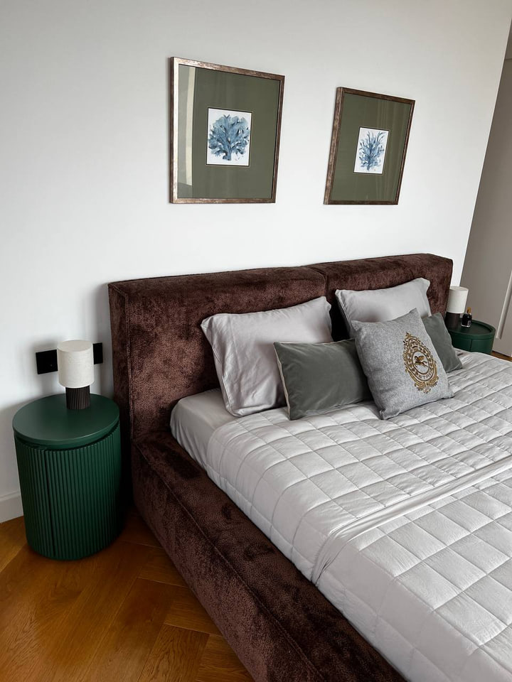 Bedroom with a brown upholstered bed and deep green bedside tables
