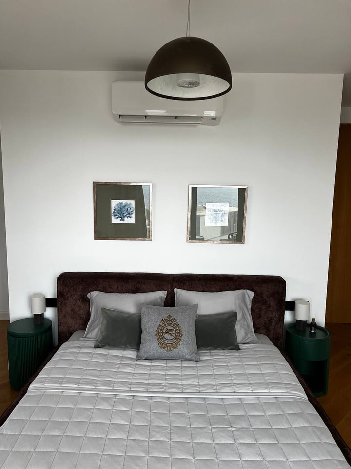 Front view of the brown upholstered bed beneath a dark pendant