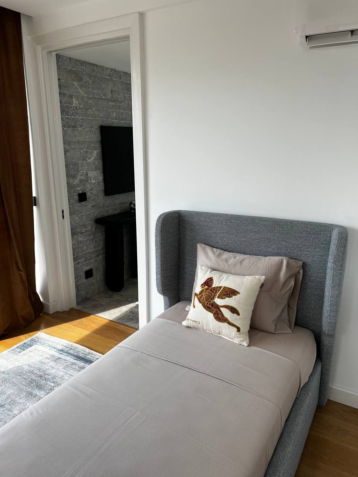 Single bedroom with a grey upholstered bed beside the stone ensuite