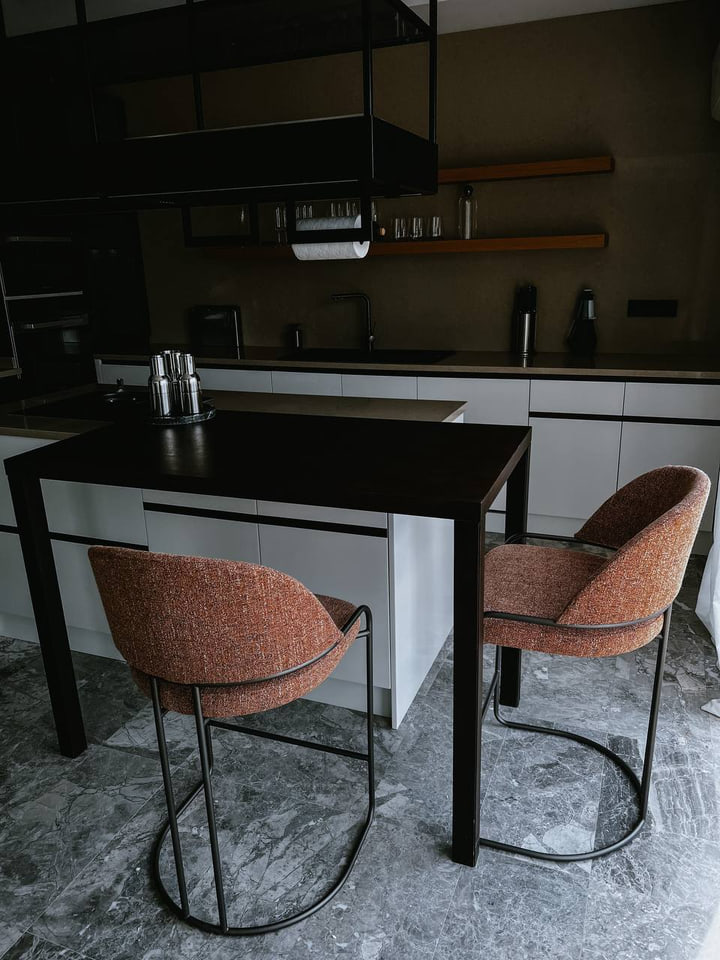 Kitchen dining table with rust-coloured chairs and dark cabinetry